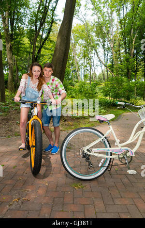 Mann in grün und Rot kariertes Hemd lehrt überrascht junges Mädchen mit dem Fahrrad in einem park Stockfoto