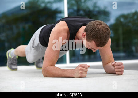 Junger Mann Ausbildung in Stadt, Ellenbogen drücken tun USV Stockfoto