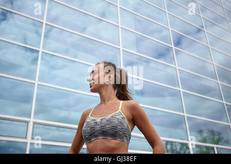 Junge Frau, training, vor Bürogebäude Stockfoto