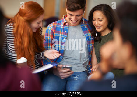 Junge männliche und weibliche Studenten lesen Smartphone im Aufenthaltsraum Stockfoto