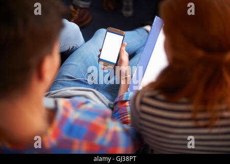 Über Schulter Blick auf junge Studentinnen und Studenten lesen Smartphone Texte im Aufenthaltsraum Stockfoto