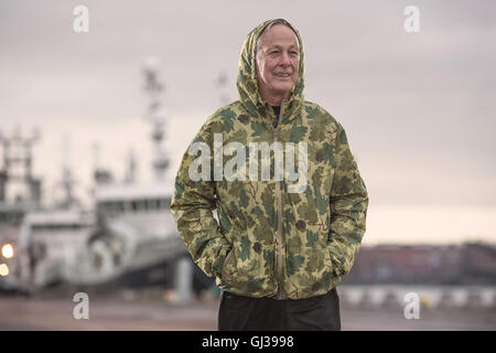 Mann trägt wasserdicht mit Kapuze Camouflage Mantel auf dockland Stockfoto