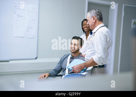 Arzt Beratung mit Mann im Rollstuhl mit Armschlinge Stockfoto