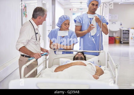 Ärzte um Patienten im Krankenhausbett Stockfoto