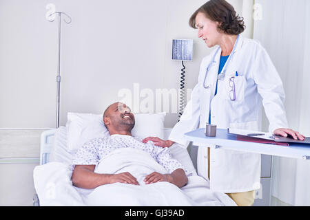 Arzt Beratung mit Patienten im Krankenhausbett liegend Stockfoto