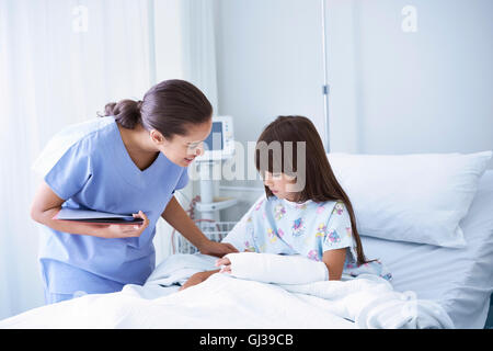 Krankenschwester, Mädchen Patient mit Gips Arm im Krankenhaus Kinderstation zu erklären Stockfoto