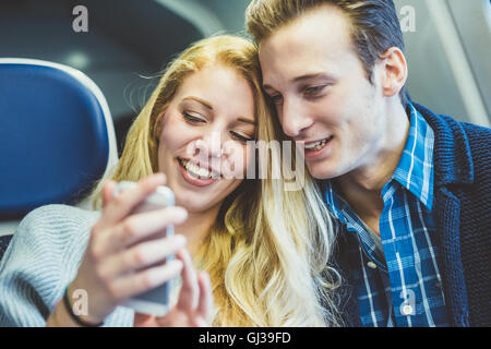 Junges Paar lesen Smartphone Texte in Zug Wagen Stockfoto