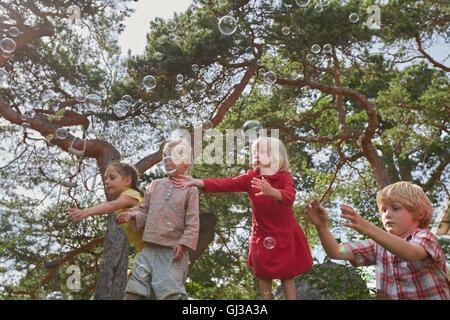 Kleine Gruppe von jungen Freunden im Freien zu spielen, beobachten Bläschen in Luft Stockfoto