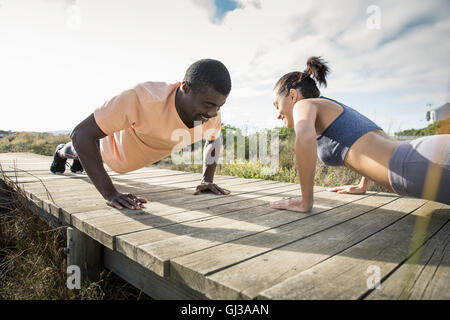 Paar tun Push ups auf hölzernen Weg Stockfoto