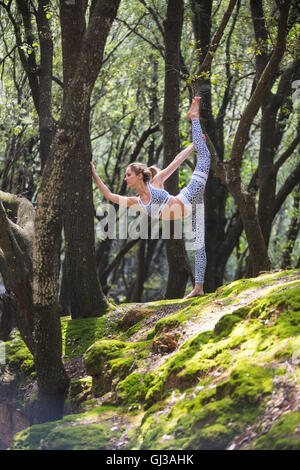 Frau auf Felsen stehend auf einem Bein Strecken Stockfoto