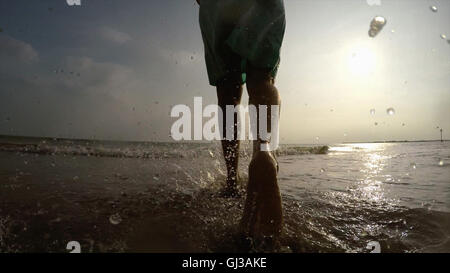 Beine der Frau auf der Küste zu Fuß im Ozean Stockfoto