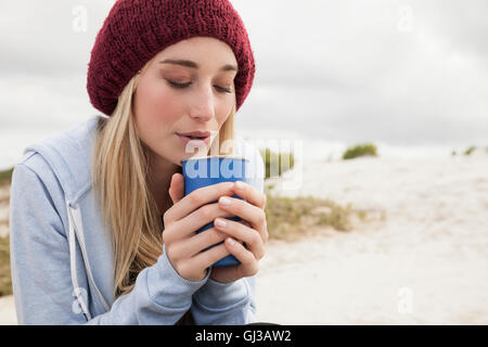 Junge Frau bläst in Kaffee an kalten Tag Stockfoto