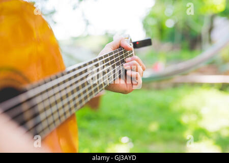 Mannes Hände akustische Gitarre spielen im Garten Stockfoto