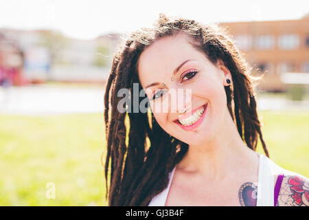 Porträt der tätowierte junge Frau mit Dreadlocks im Stadtpark Stockfoto