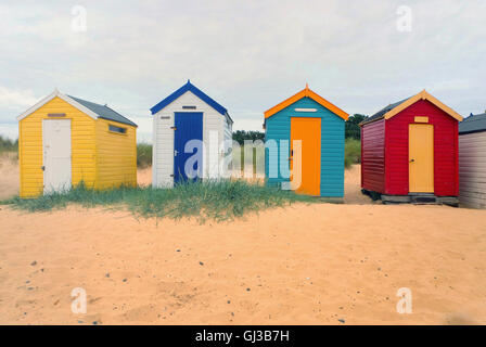 Blick nach vorne auf eine Zeile vier mehrfarbigen Strand Hütten, Southwold, Suffolk, UK Stockfoto