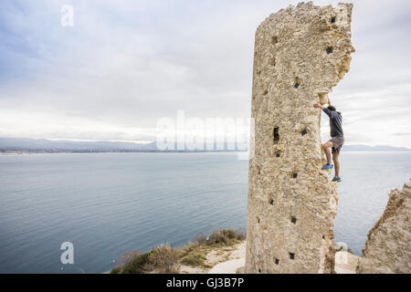 Männliche Kletterer zerstörten Kletterturm an Küste, Cagliari, Italien Stockfoto