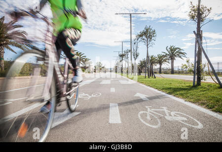 Bewegungsunschärfe Nahaufnahme von Radfahrer tragen high Vis Jacke Radfahren in Radweg Stockfoto