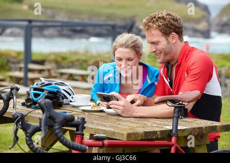 Radfahrer mit Handy an Picknick-Tisch mit Blick auf Meer Stockfoto