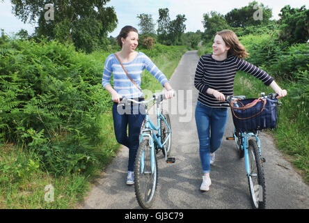 Zwei junge Erwachsene Fahrräder schieben und entlang der Landstraße im Chat Stockfoto