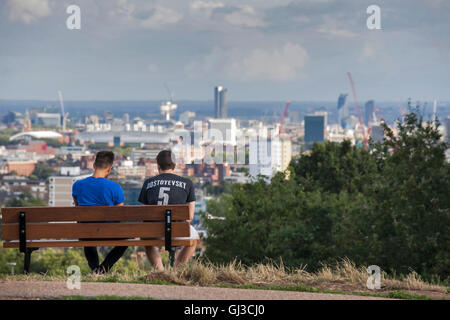 LONDON - 10. MAI 2015. Zwei Männer im T-shirt mit "Dostojewski" Schild sitzen auf Bank, den Blick auf London in Primrose Hill Stockfoto