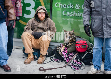 Chicago, Illinois - 28. November 2014: A Chicago Obdachlosen Mann und sein Hund sitzen auf dem Bürgersteig an einem kalten, kalten Tag Ende November. Stockfoto