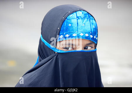 Porträt eines muslimischen Mädchens. Ihr Gesicht ist mit schwarzem Tuch bedeckt. Stockfoto