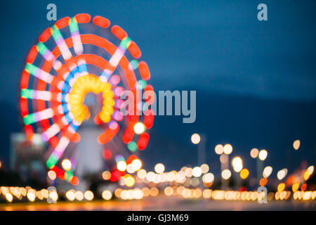 Abstrakte Motion Blur Bild hell bunt beleuchteten Riesenrad In Stadt Vergnügungspark auf schwarz blau Abend Himmel Bokeh Stockfoto