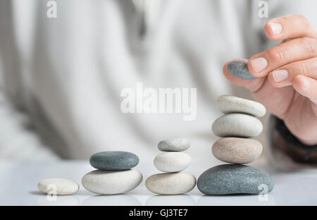 Horizontales Bild eines Mannes Stapeln Kieselsteine auf einem Tisch mit Exemplar für Text. Konzept des Risikomanagements und Reichtum. Stockfoto