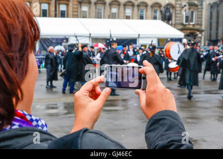 Glasgow, UK. 12. August 2016. Trotz starkem Regen und starkem Wind einige Touristen noch stellte sich heraus, dass die Pipe Bands, gab kostenlose Konzerte auf dem George Square und rund um die Innenstadt zu unterstützen. Die einwöchige Festival der Dudelsack Musik endet am Samstag mit dem spektakulären Welt Pipeband Meisterschaft, an der alle Bands. Credit: Findlay/Alamy leben Nachrichten Stockfoto