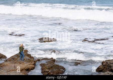 Eine Frau, die Wellen im Carisbrook Creek entlang der Great Ocean Road zu fotografieren. Stockfoto