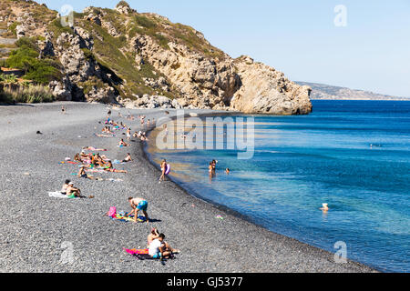 Lokalen und touristischen Menschen am Strand Mavra Voliá. Mavra Voliá ist ein Strand mit kleinen schwarzen vulkanischen Kieselsteinen in der Nähe von Emporios Dorf Stockfoto