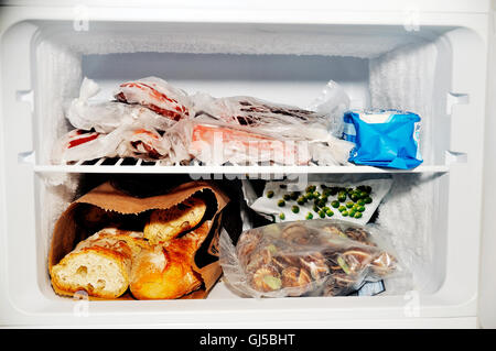 Gefrierfach eines Kühlschranks mit Fleisch sowie gefrorenes Gemüse und Brot Stockfoto