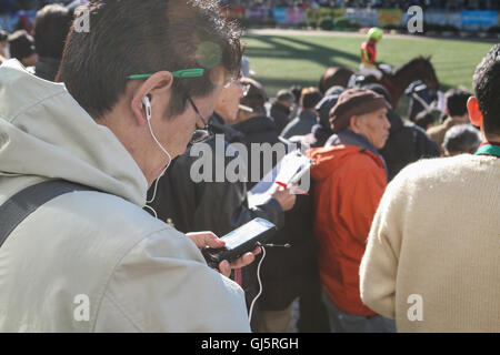 Börsenspekulanten überprüfen die Pferde an der Parade Ring mit den Jockeys für Rennen 10 montiert.  Im allgemeinen Eintrittspreis des Yen 200, Stockfoto