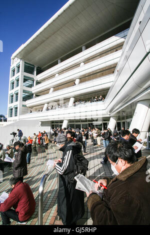 Börsenspekulanten überprüfen die Pferde an der Parade Ring mit den Jockeys für Rennen 10 montiert. Großer Stand mit sechs Stockwerken gehört Stockfoto