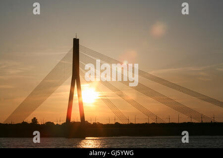 Die Kabelbrücke (bekannt als Vansu kippt in lettischer Sprache) ist eine Schrägseilbrücke, die die Daugava überquert. Bei Sonnenuntergang / Sonnenuntergang. Foto von der Altstadt entfernt, im Zentrum von Riga, die Hauptstadt Lettlands. Mai. Stockfoto