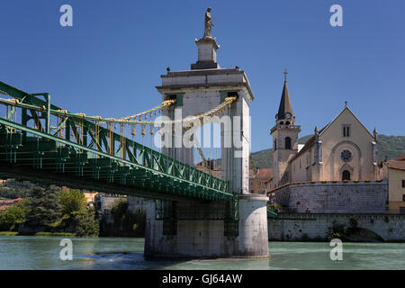 Hängebrücke über den Fluss mit Kirche im Hintergrund unter blauem Himmel Stockfoto