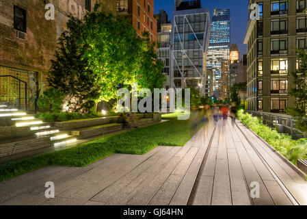 Die High Line-Promenade beleuchtet in der Dämmerung umgeben von modernen und Altbauten in Chelsea, Manhattan, New York City Stockfoto