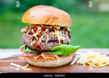 Beefburger mit gebratenen Zwiebeln, Speck und Zeichenfolge Pommes in Brioche Brötchen Stockfoto