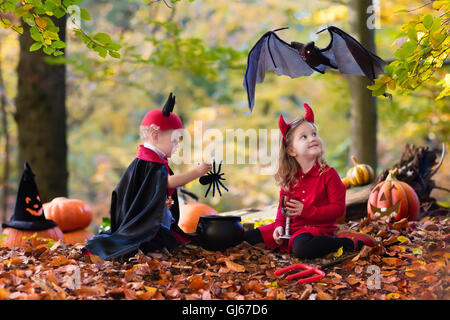 Zwei lustige Kinder tragen Teufel und Vampir Kostüm mit roten Hörnern und Trident Süßes oder Saures an Halloween. Stockfoto