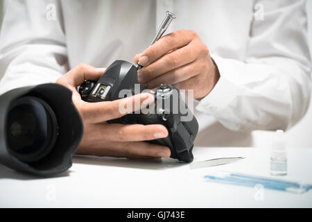 Mann, Reinigung und Reparatur einer Digitalkameras mit Schraubenzieher und Sensor Reinigungs-Kit. Stockfoto