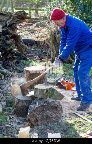 Mann Chopping Protokolle mit langen behandelt Axt für Brennholz. Holzbefeuerter Ofen. Stockfoto