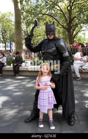 6-jährige Mädchen posiert für ein Foto mit Batman in Leicester Square im Zentrum von London Stockfoto