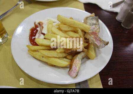 Pommes Frites mit Fisch auf einem weißen Teller wird zum Abendessen serviert Stockfoto