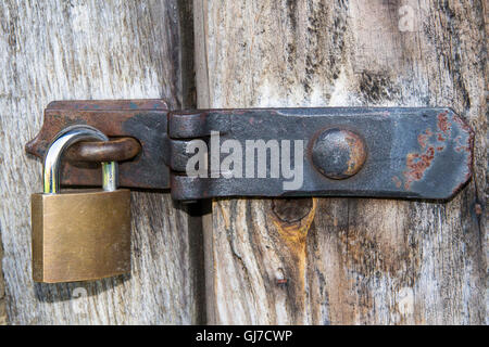 Nahaufnahme eines Vorhängeschlosses und altes Metall Hasp und Heften auf einer alten Holztür Stockfoto