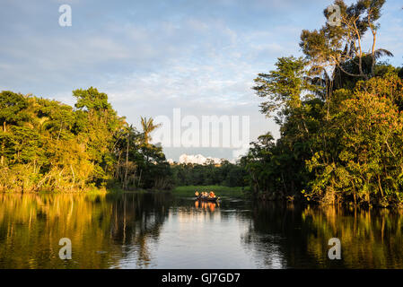 Ein Kanu mit Touristen über Amazon bei Sonnenuntergang paddeln. Yasuni-Nationalpark in Ecuador, Südamerika. Stockfoto