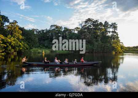 Ein Kanu mit Touristen über Amazon bei Sonnenuntergang paddeln. Yasuni-Nationalpark in Ecuador, Südamerika. Stockfoto