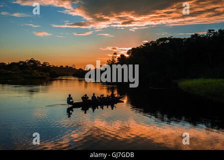 Ein Kanu mit Touristen über Amazon bei Sonnenuntergang paddeln. Yasuni-Nationalpark in Ecuador, Südamerika. Stockfoto