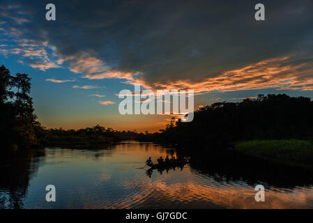 Ein Kanu mit Touristen über Amazon bei Sonnenuntergang paddeln. Yasuni-Nationalpark in Ecuador, Südamerika. Stockfoto