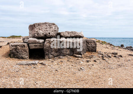 Massive Platten aus grau-braun Portland limestone Form einer niedrigen rechteckige Box Struktur im Gegensatz zu Kies der Strand, an dem es gebaut wird Stockfoto