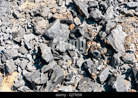 Schieben Sie ein Haufen von gebrochenen und gerissenen Felsen liegt an einem Strand aus Sand und Kies durch ein Land von einer angrenzenden Klippe Stockfoto